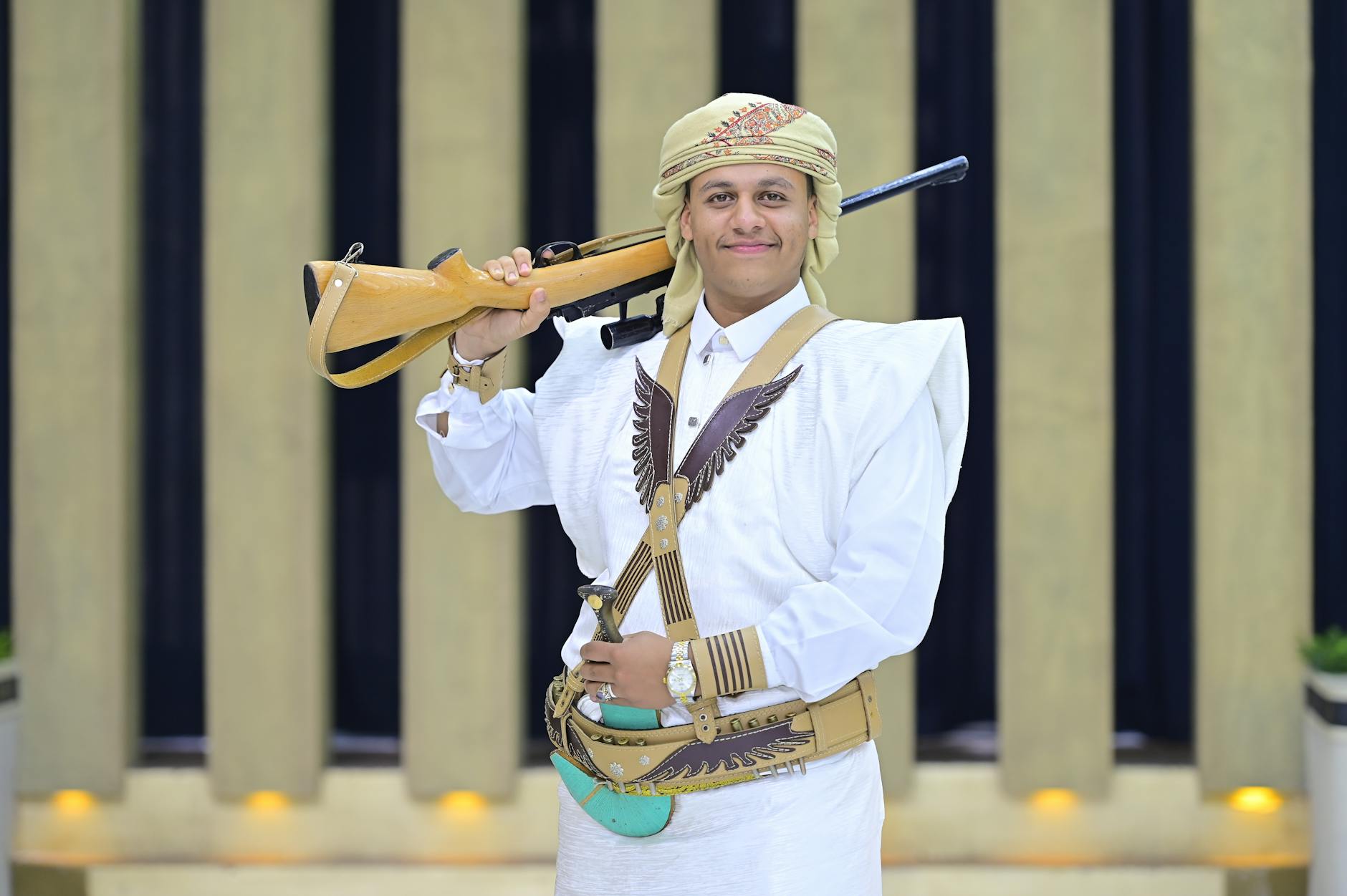 A Yemeni man proudly wears traditional attire with a rifle, showcasing cultural heritage.