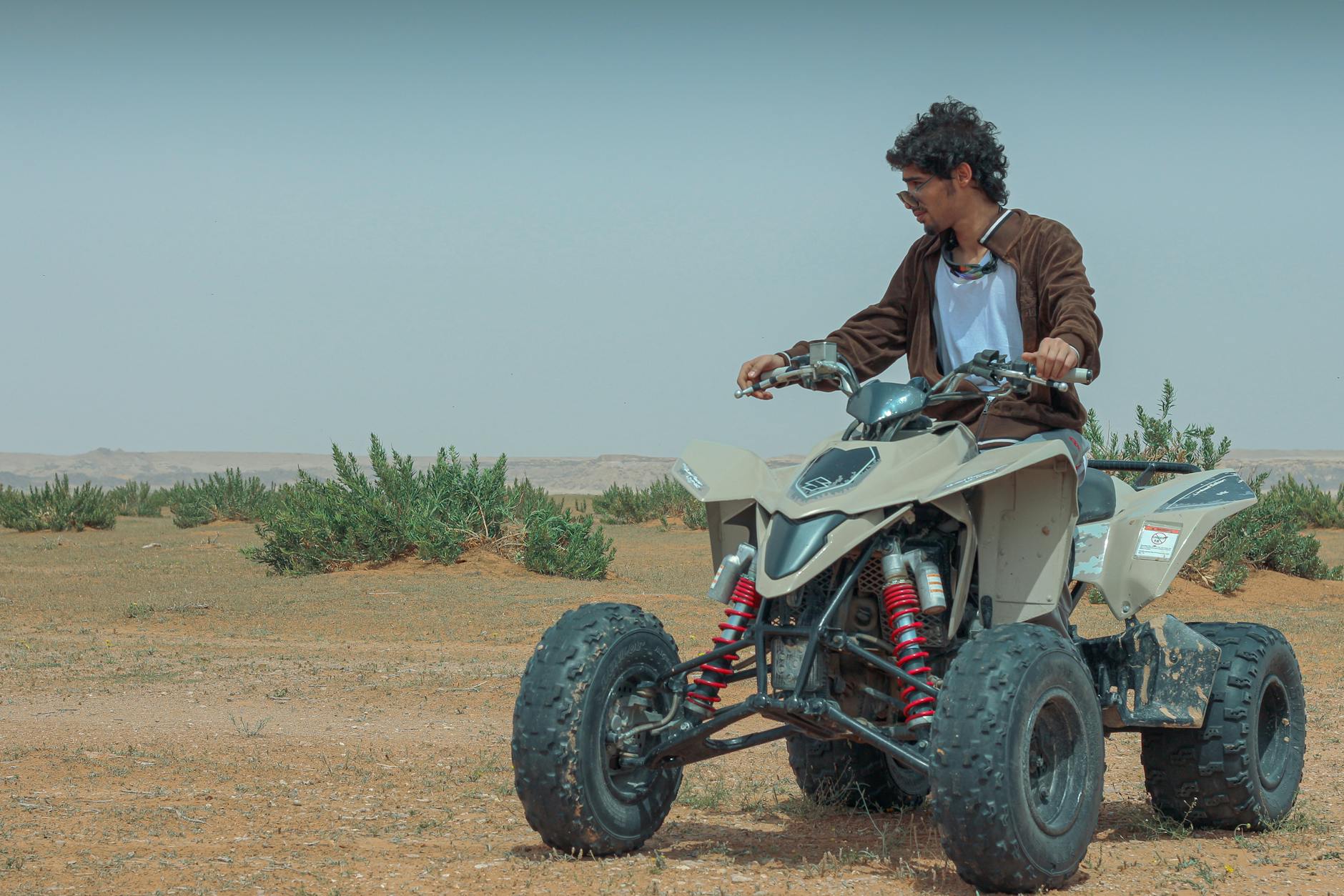 Young man riding a quad bike in the vast Saudi Arabian desert near Riyadh, enjoying adventure sports.